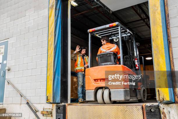 ein thema für die sicherheit am arbeitsplatz in industrielagern.  ein manager oder vorgesetzter verhindert, dass ein gabelstaplerfahrer über eine laderampe zurücklegt. - hazardous workplace stock-fotos und bilder