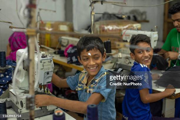 Child labours making fun and chit-chatting with each other while working in a local ready made garments factory at Narayanganj, Bangladesh on August...