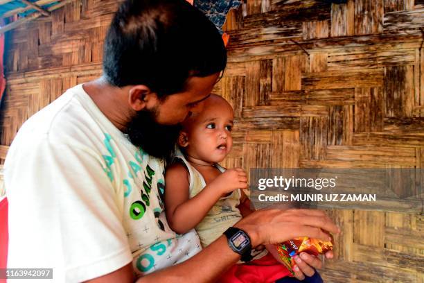 Rohingya refugee Mohammad Selim interacts with his son Ahmad Shah, who was born two years ago when a brutal military clampdown eventually drove away...