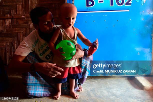 Rohingya refugee Mohammad Selim interacts with his son Ahmad Shah, who was born two years ago when a brutal military clampdown eventually drove away...