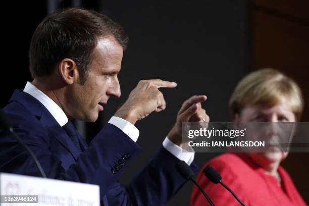 French President Emmanuel Macron gestures as German Chancellor Angela Merkel listens on during a press conference on the situation in Sahel during...