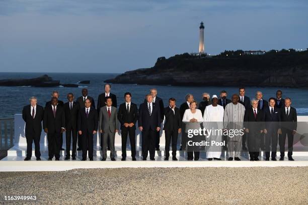 Leaders and guests pose for a family picture with the Biarritz lighthouse in the background on the second day of the annual G7 summit: L-R Britain's...