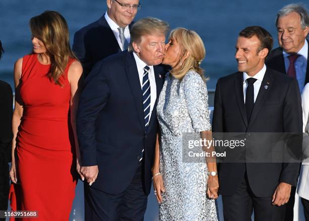 French President's wife Brigitte Macron kisses US President Donald Trump as G7 leaders and guests gather for a family picture in front of the...