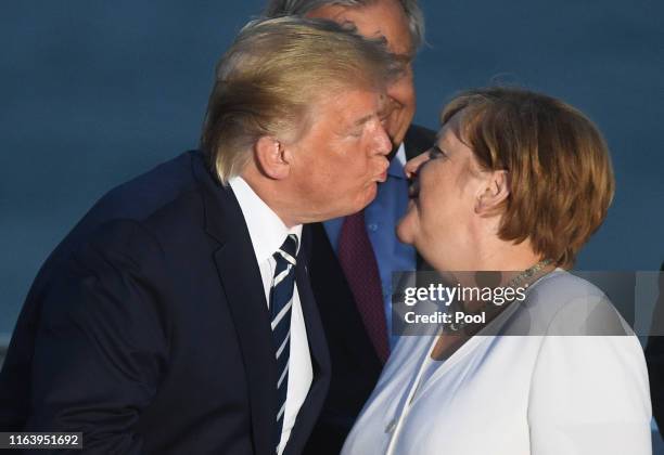 President Donald Trump kisses Germany's Chancellor Angela Merkel as G7 leaders and guests gather for a family picture in front of the Biarritz...