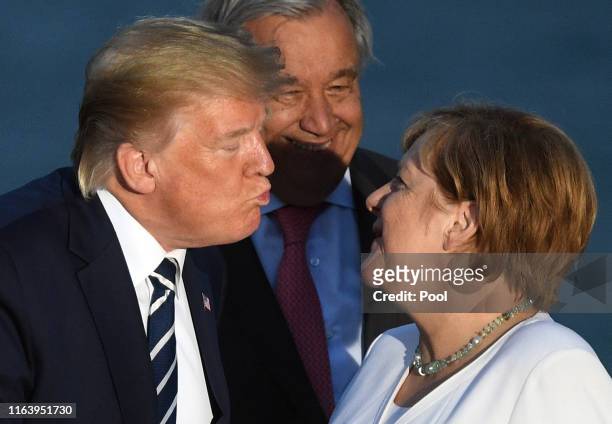 President Donald Trump kisses Germany's Chancellor Angela Merkel as G7 leaders and guests gather for a family picture in front of the Biarritz...