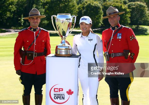 Jin Young Ko of Korea poses with the CP Women's Open Championship Trophy and Canadian Mounties following the final round at Magna Golf Club on August...