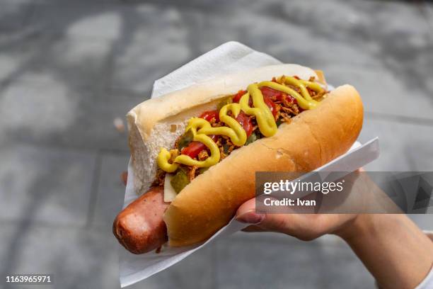 woman's hand holding hot dog - hot dog - fotografias e filmes do acervo