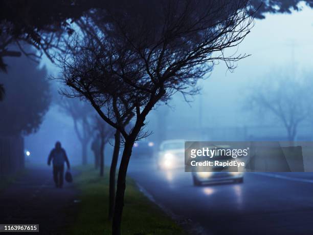 commuters' cars drive through fog on city street at twilight - driving in fog stock pictures, royalty-free photos & images