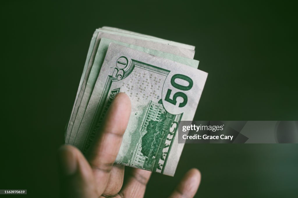 Close-Up of Hand Holding Folded Stack of US Currency