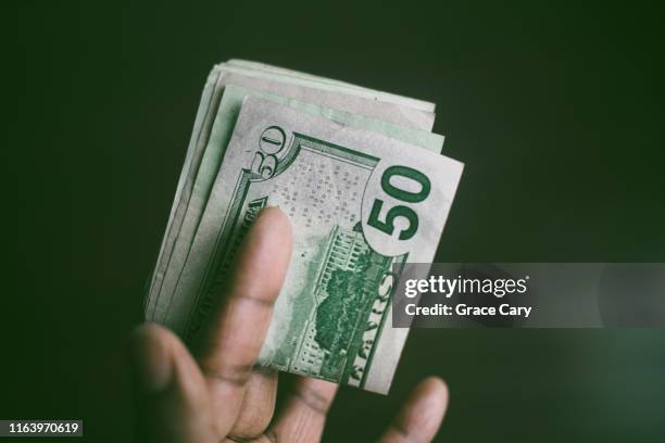 close-up of hand holding folded stack of us currency - 50 dollar bill stock pictures, royalty-free photos & images