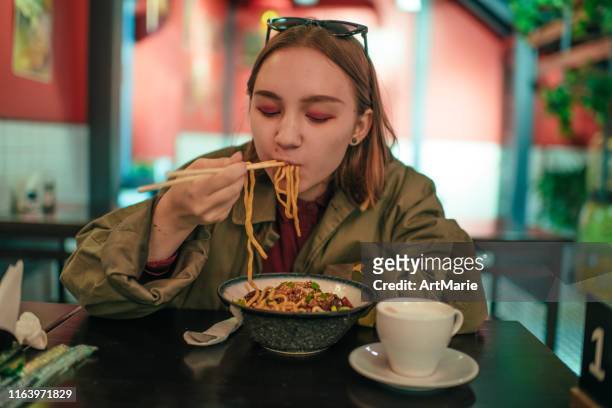 young girl eating chinese food in a restaurant in autumn - ramen noodles stock pictures, royalty-free photos & images