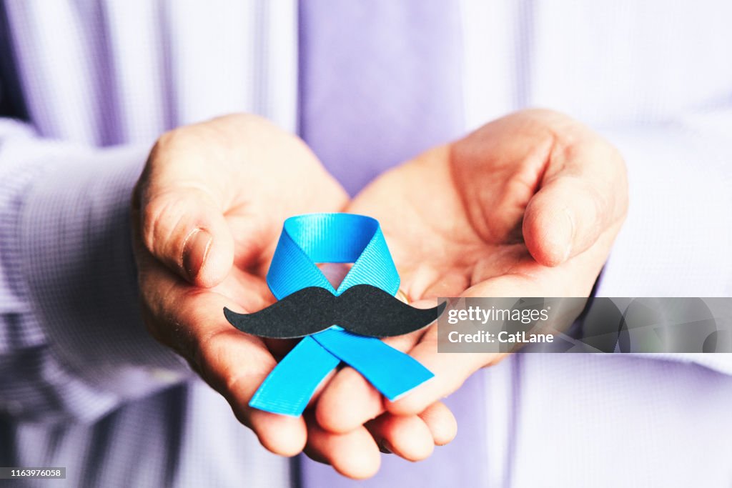 Mains mâles retenant le ruban de conscience de cancer de la prostate avec la moustache