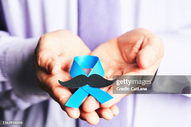 mannelijke handen houden prostaatkanker bewustzijn lint met snor - moustaches stockfoto's en -beelden