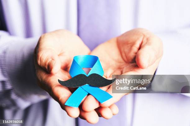 male hands holding prostate cancer awareness ribbon with mustache - stroke month stock pictures, royalty-free photos & images