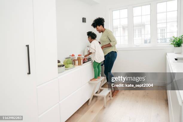 ontrommeling van de keuken met de hulp van de dochter - huishoudklusjes stockfoto's en -beelden