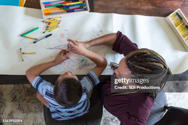 juega a los colores del terapeuta con el niño con síndrome de down - children art fotografías e imágenes de stock