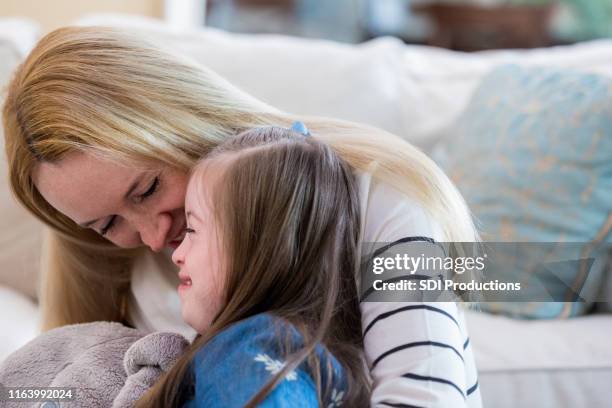 mid adult mom snuggles with daughter - mental disability stock pictures, royalty-free photos & images