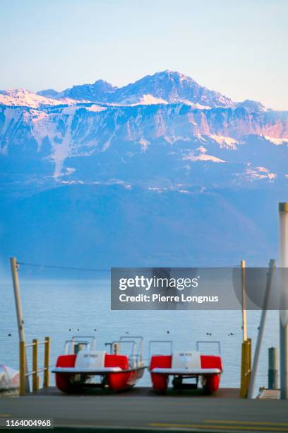 two pedal boats on the shore of lake geneva in lausanne, ouchy district, alps in backdrop - lausanne - fotografias e filmes do acervo