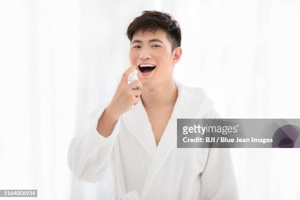 young chinese man using mouth spray - mouth spray stock pictures, royalty-free photos & images