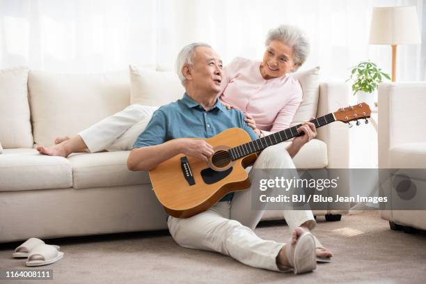 happy senior chinese couple playing the guitar in living room - tocadora de violão imagens e fotografias de stock