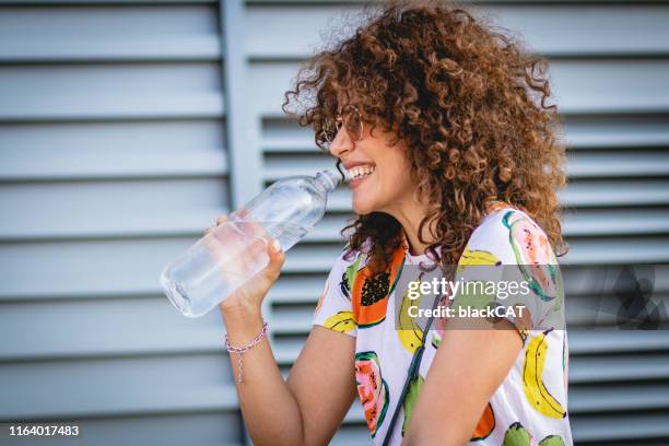 hydratation im sommer. eine junge frau trinkt wasser - woman drinking water from bottle stock-fotos und bilder