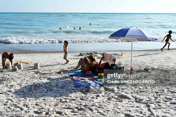 Family sunbathe as children build sandcastles on the "Spiagge Bianche" beach, in Rosignano Solvay, a town in Italy's central Tuscany region, on July...