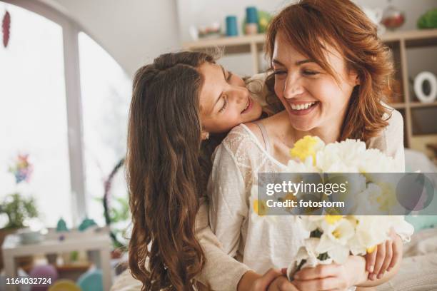 daughter giving flowers to her mother at home - mothers day flowers stock pictures, royalty-free photos & images