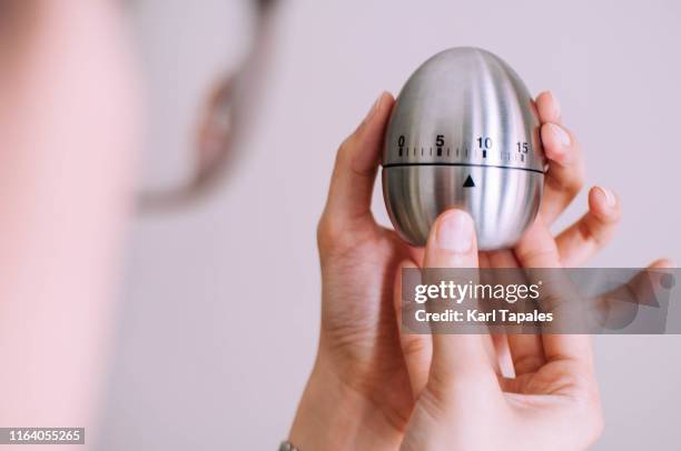 a young woman is holding a metal kitchen egg timer - egg timer stock-fotos und bilder