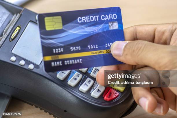 cashier hand holding a credit card over edc machine or credit card terminal to made a payment on his desk. this is fake credit card. - electronic data capture stock pictures, royalty-free photos & images