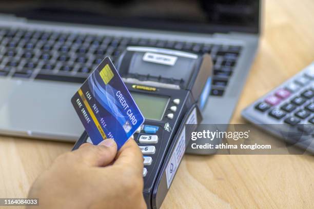 cashier hand holding a credit card over edc machine or credit card terminal with calculator and glasses. - electronic data capture stock pictures, royalty-free photos & images