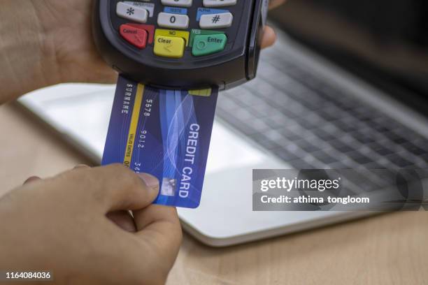 cashier hand holding a credit card over edc machine or credit card terminal to made a payment on his desk. this is fake credit card. - electronic data capture stock pictures, royalty-free photos & images