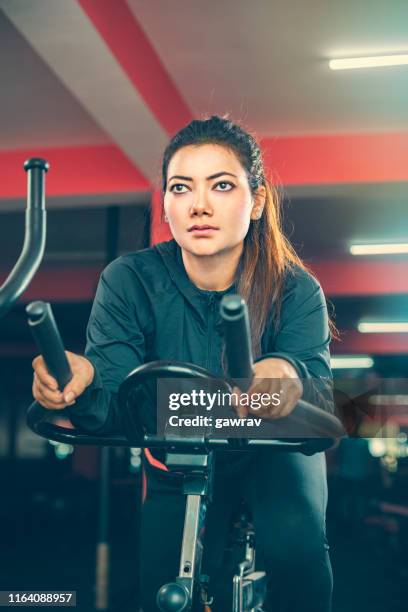 beautiful woman does cardio exercise on air bike in gymnasium. - cycling gym stock pictures, royalty-free photos & images