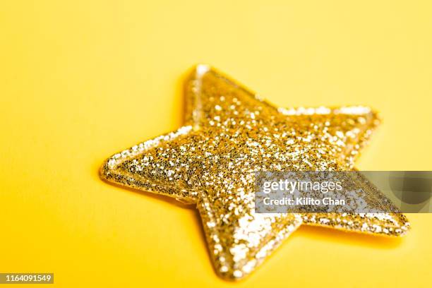 a golden star against yellow background - abstract shap stock pictures, royalty-free photos & images