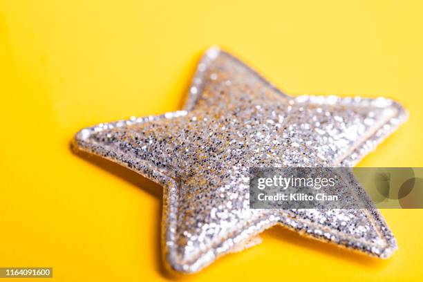 a silver star against yellow background - abstract shap stock pictures, royalty-free photos & images