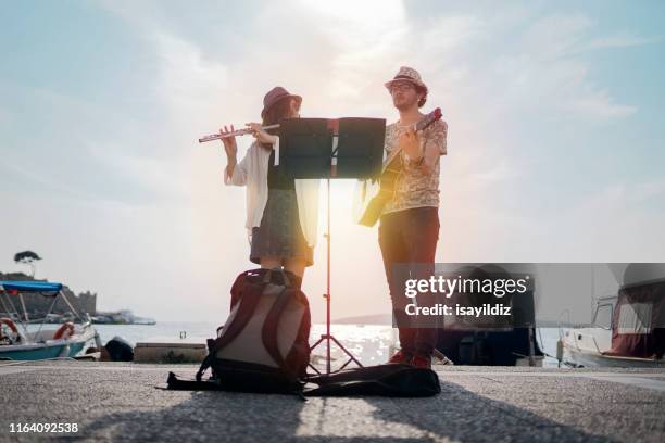 flutist and her guitarist friend are playing on the street - street performer stock pictures, royalty-free photos & images