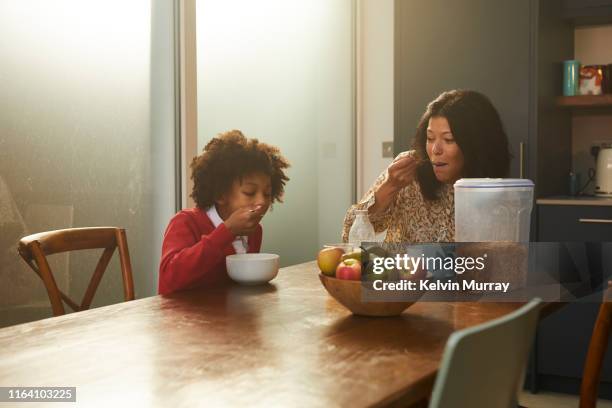 A girl wearing school uniform having breakfast at home with mother before school