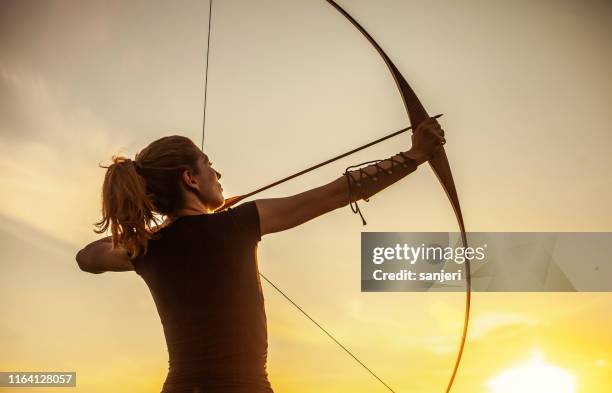 donna che punta al tiro con l'arco - arco e freccia foto e immagini stock