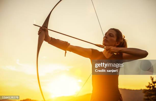 donna che punta al tiro con l'arco - arco frecce foto e immagini stock