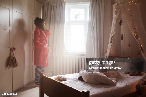 Mother waking up daughter in bedroom in the morning