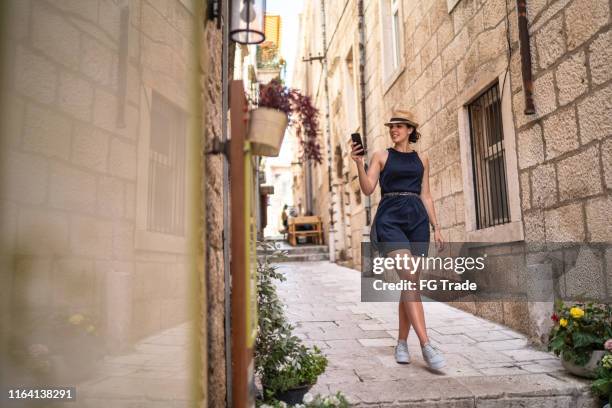 mooie vrouw met behulp van telefoon en wandelen in dubrovnik, kroatië - dubrovnik stockfoto's en -beelden