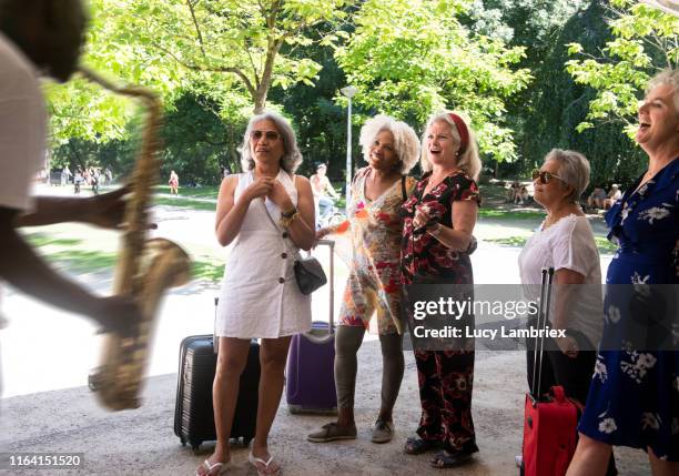 senior women enjoying street musician's saxophone music - street performer stock pictures, royalty-free photos & images