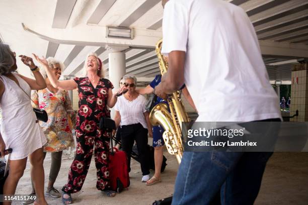 senior women enjoying street musician's saxophone music - street artist 個照片及圖片檔