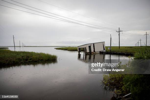 Small covered fishing dock dips into coastal waters near Bayou Lafourche in Leeville, Louisiana on August 25, 2019. According to researchers at the...
