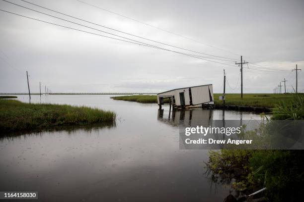 Small covered fishing dock dips into coastal waters near Bayou Lafourche in Leeville, Louisiana on August 25, 2019. According to researchers at the...