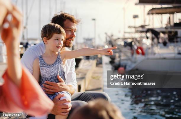 a father with small girl outdoors on dock, resting. - family yacht stock pictures, royalty-free photos & images