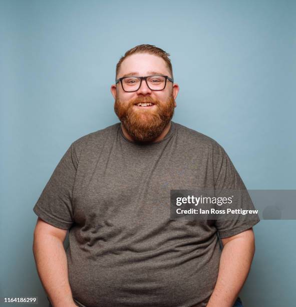 overweight bearded hipster on blue background - chubby men stock-fotos und bilder