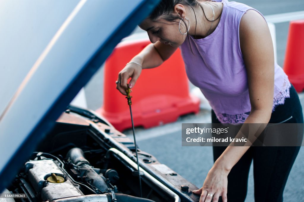 Girl checks the oil in the car's engine