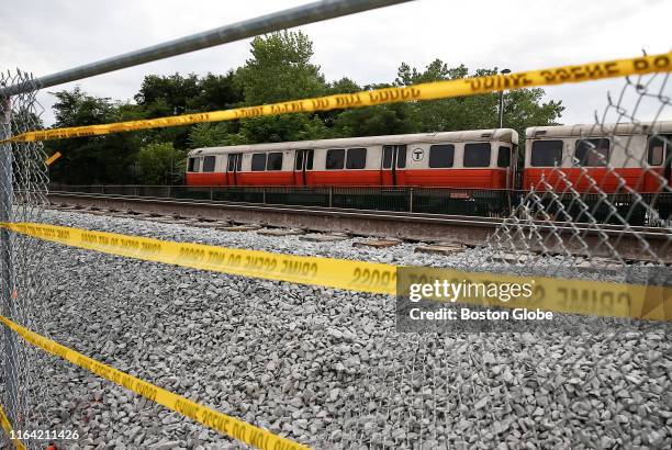 Police tape hangs across a hole cut in a fence to help evacuate Orange Line passengers due to a fire in Medford, MA on Aug. 23, 2019. Service on part...