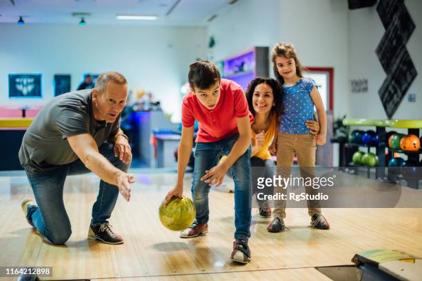 junge bowling mit eltern und schwester - family bowling stock-fotos und bilder