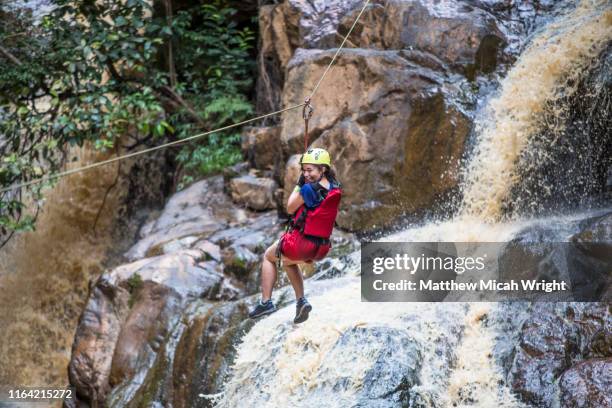 canyoning is one of the most popular activities in dalat. a girl ziplines down a waterfall. - ziplining stock pictures, royalty-free photos & images